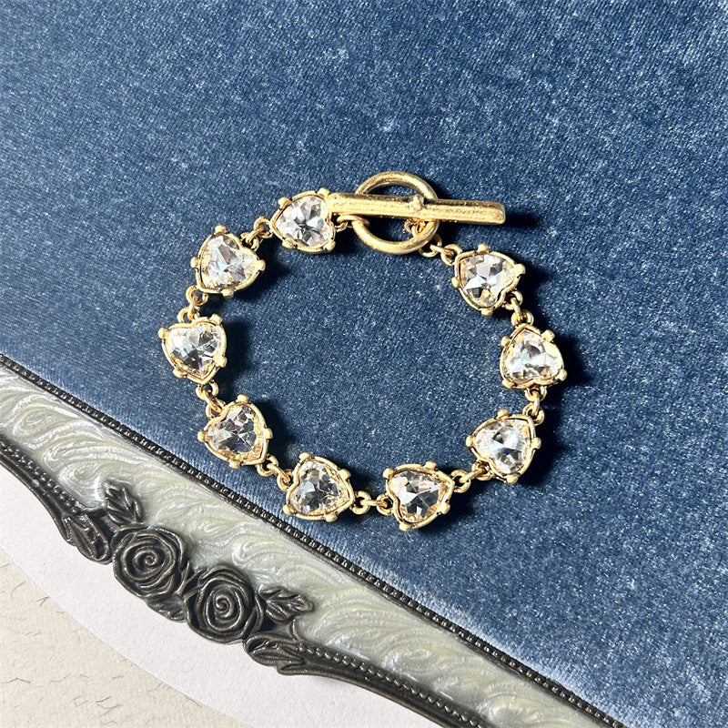 White crystal heart link bracelet with gold-tone chain and round clasp bar