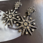 Silver-tone eight-point star drop earrings with clear crystal pavé and sparkle stones.