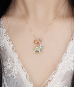 Enamel rocking horse necklace on neckline with gold chain, blue horse charm and cup pendant
