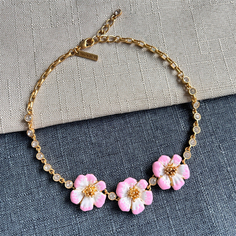 Gold chain pendant necklace with pink enamel cherry blossom flowers and round crystal accents.