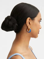 Ombré resin U-shaped hoop earrings on ear, gold-tone with blue and purple gradient