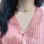 Pearl choker necklace with gold square center tag on neckline