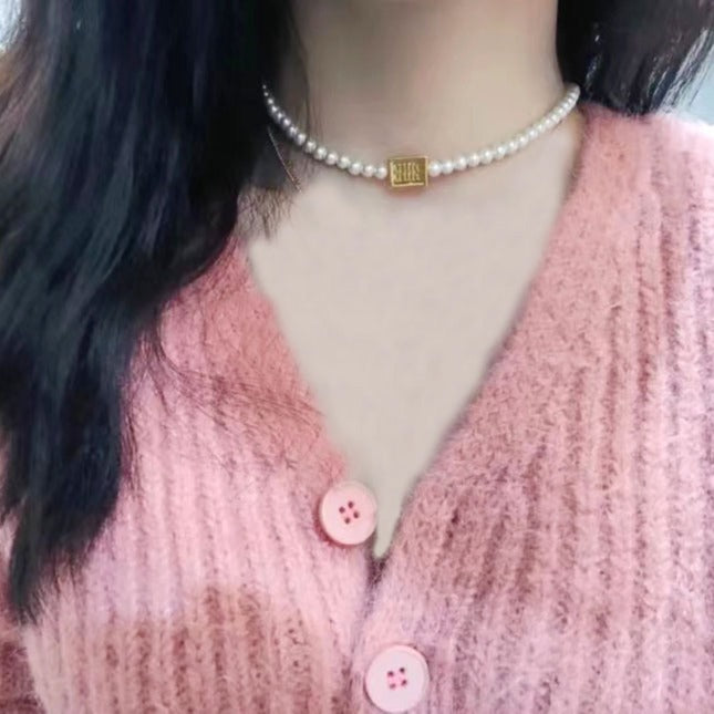 Pearl choker necklace with gold square center tag on neckline