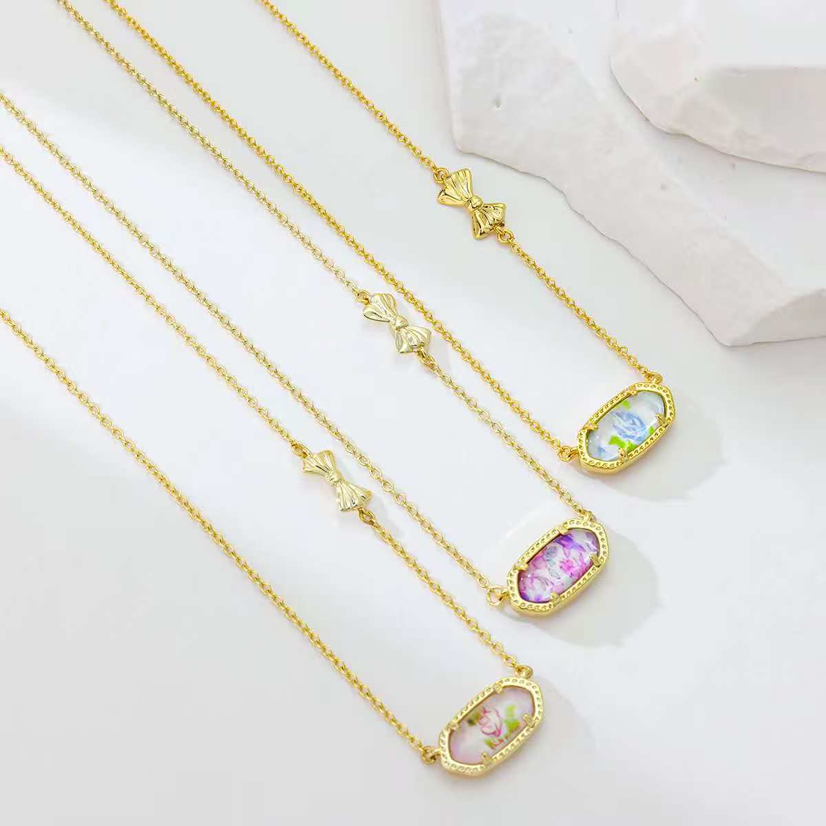 Bow rose print pendant necklace with blue, pink, and purple oval pendants and bow charms