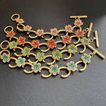 Buntes Blumenarmband mit goldfarbenen Haken und Ziersteinen in Rot, Grün und Rosa