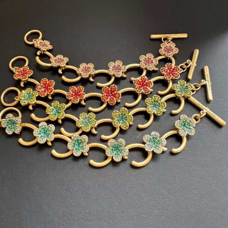 Buntes Blumenarmband mit goldfarbenen Haken und Ziersteinen in Rot, Grün und Rosa