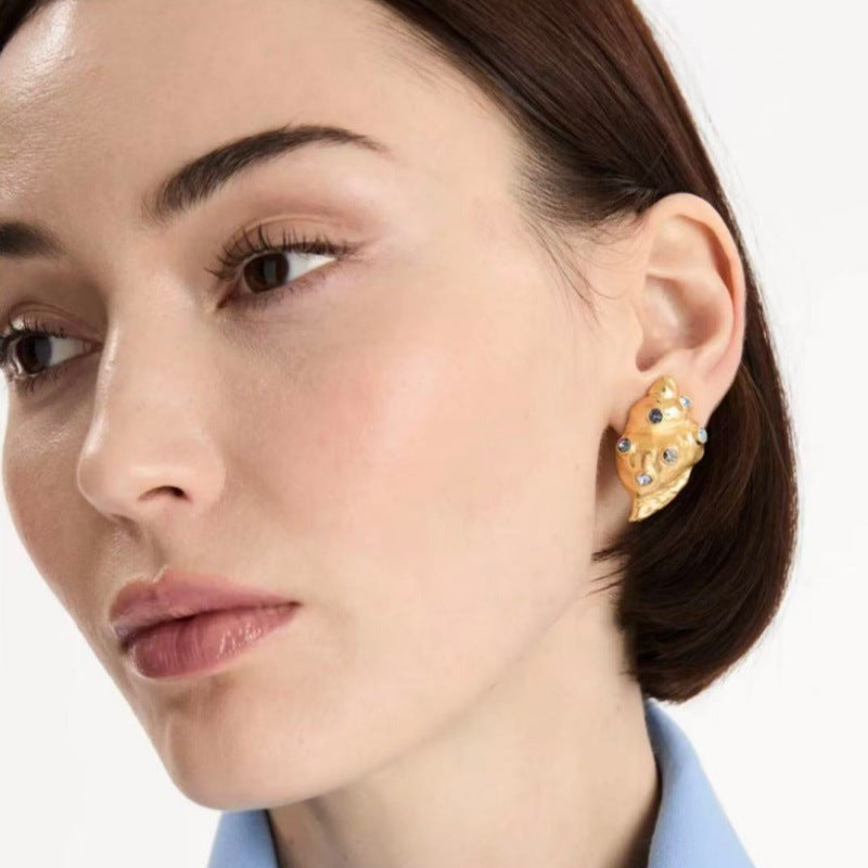 Oscar de la Renta conch earrings on model, gold shell with blue stones