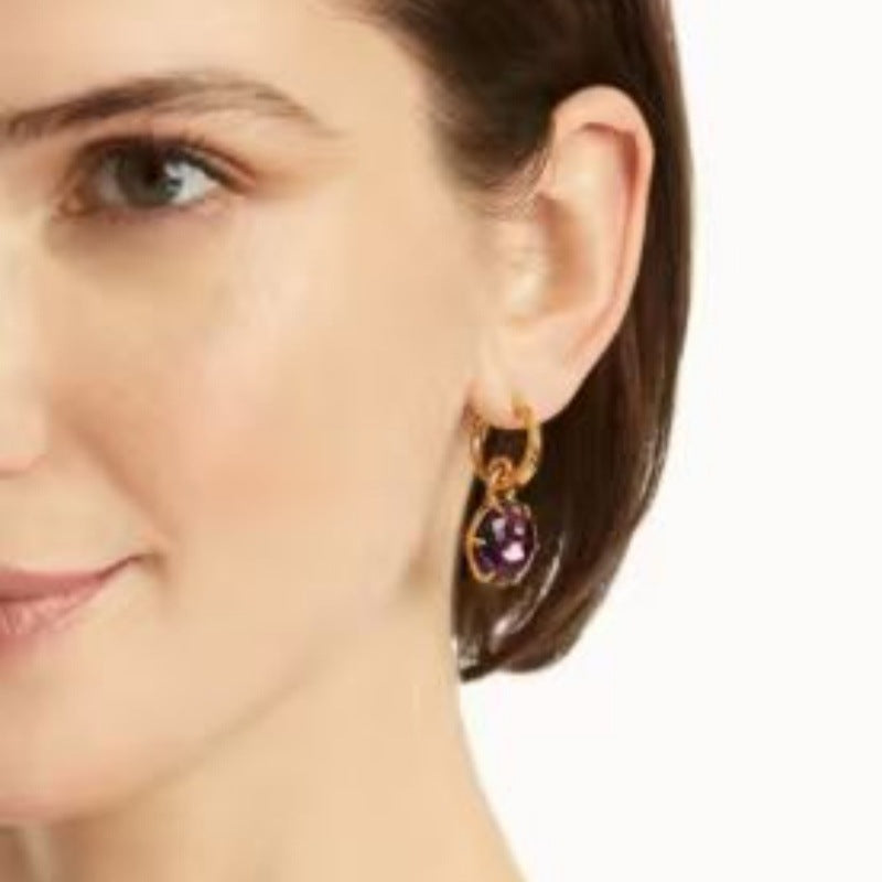 On-ear view: gold-tone hoop earrings with round purple crystal drop pendant