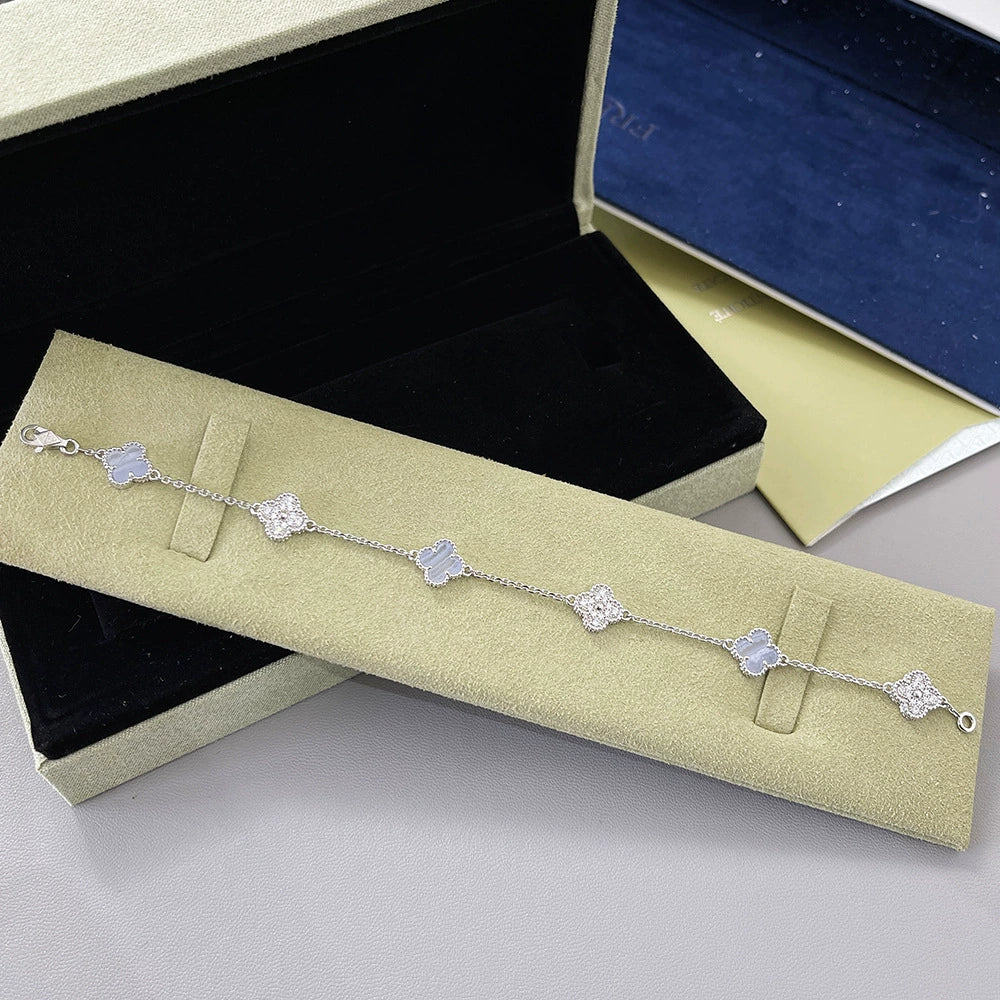 Silberfarbenes Armband mit hellblauen Vierblatt-Anhängern und strassbesetzten Gliedern