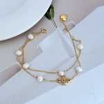 Heart-shaped charm bracelet in gold with freshwater pearls and crystal flower centerpiece