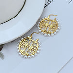 Gold round logo metal earrings with pearl border and drop hook closure