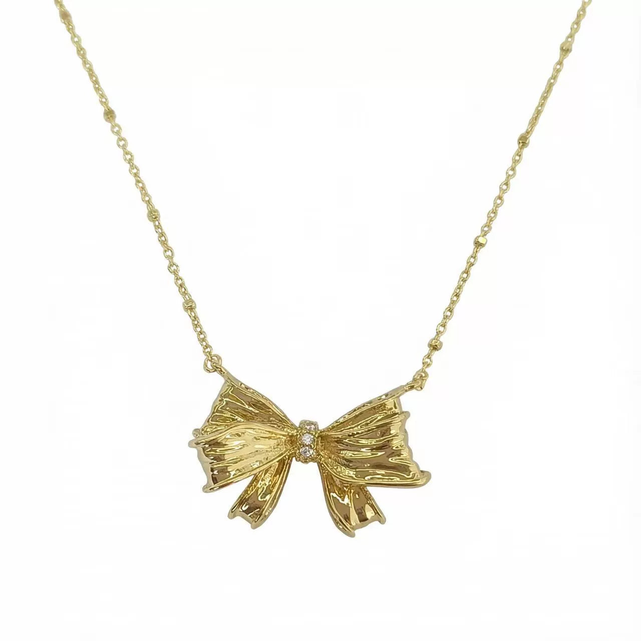 Gold bow pendant necklace with small round crystal in center