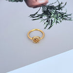 Gold-tone logo ring with round bezel and small clear stones on openwork plaque