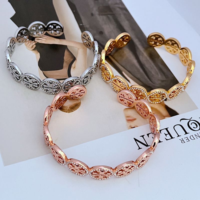Stacked metal-tone diamond-studded logo bangles with circular openwork discs