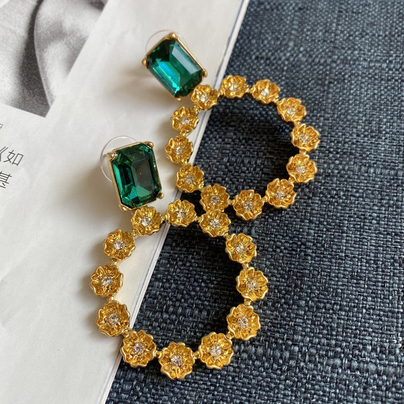 Large round earrings with emerald green square stones and gold-tone floral ring trim