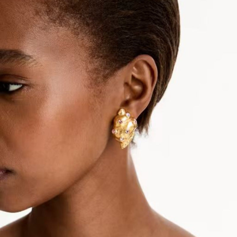 Conch earrings on model: gold-tone shell with pink and clear stones