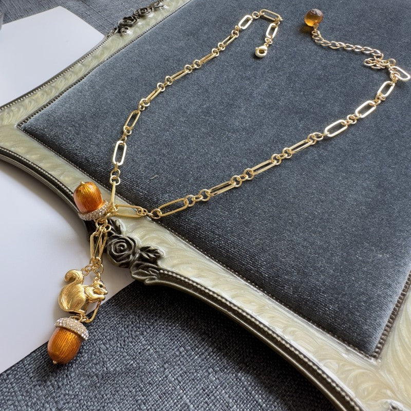 Gold pendant necklace with squirrel charm and brown pinecone beads on chain links