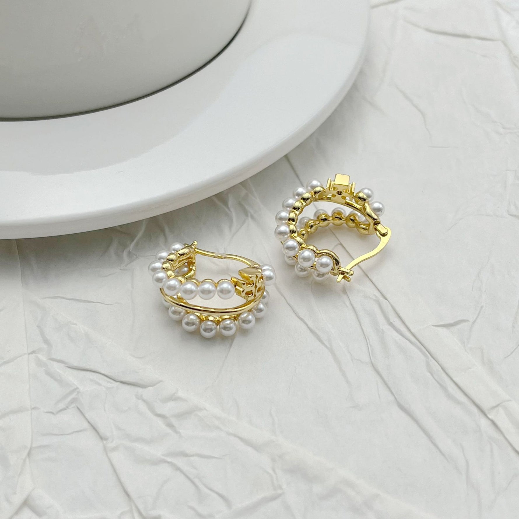 Gold-tone faux pearl hoop earrings with decorative outer bezel