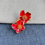 Red enamel floral stud earrings with gold-tone petals and round beaded center