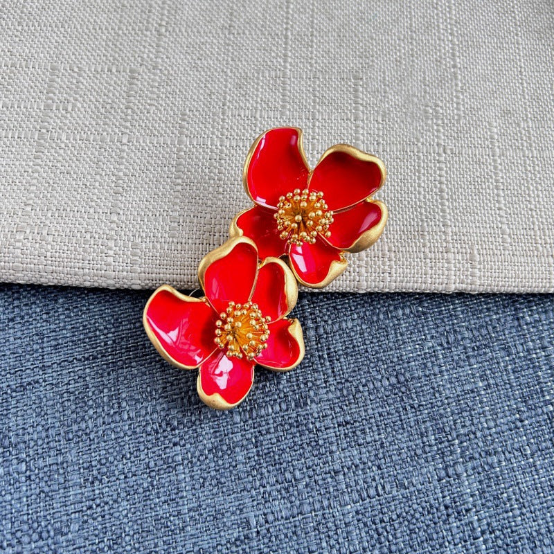 Red enamel floral stud earrings with gold-tone petals and round beaded center