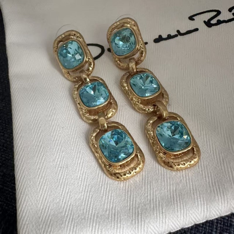 Blue crystal long drop clip-on earrings with three oval stones in gold-tone frames