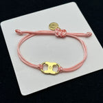 Light pink woven adjustable drawstring bracelet with gold clover enamel charm and coin