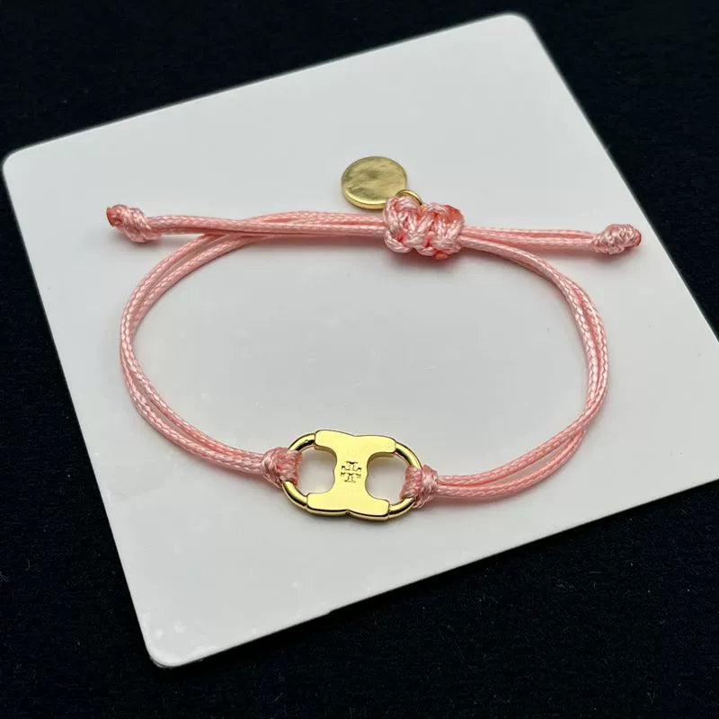 Light pink woven adjustable drawstring bracelet with gold clover enamel charm and coin