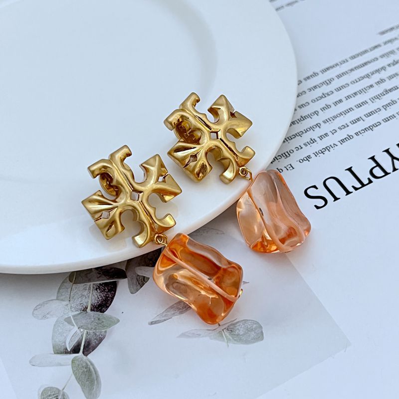 Orange irregular acrylic logo pendant earrings with gold-tone geometric cross and bell-shaped drops