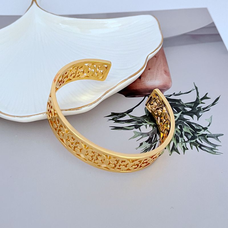 Goldener offener Logo-Armreif mit durchbrochenem Metallmuster