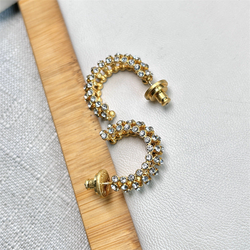 Gold-tone cubic zirconia C-hoop earrings with yellow and clear stones; angled view