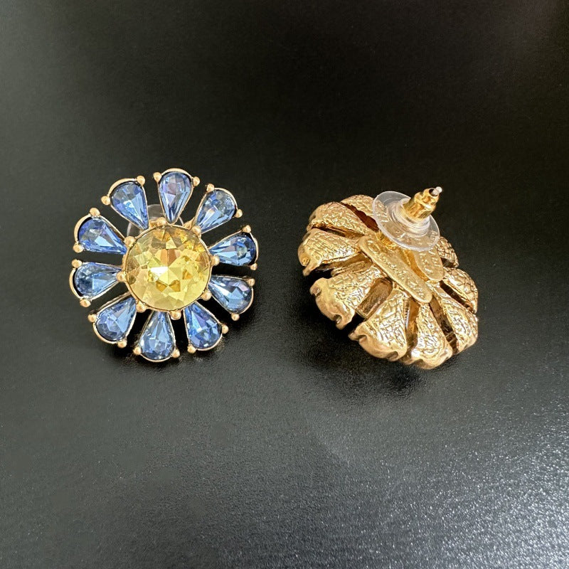 Sunburst flower stud earrings with blue teardrop stones and yellow center, gold-tone pair