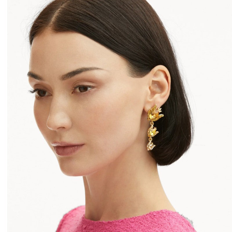 Gold-tone floral zircon drop earrings with amber-and-clear stones worn on model