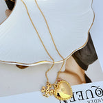 Gold heart pendant necklace with mother-of-pearl shell inlay and floral rosette charm