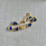 Blue matte heart bracelet close-up, gold-tone chain with heart charms