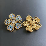 Blue floral stud earrings with gold openwork backing and post closure