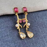 Clip-on earrings with gold branch design, pink stones, white pearls, and crystal drop charms