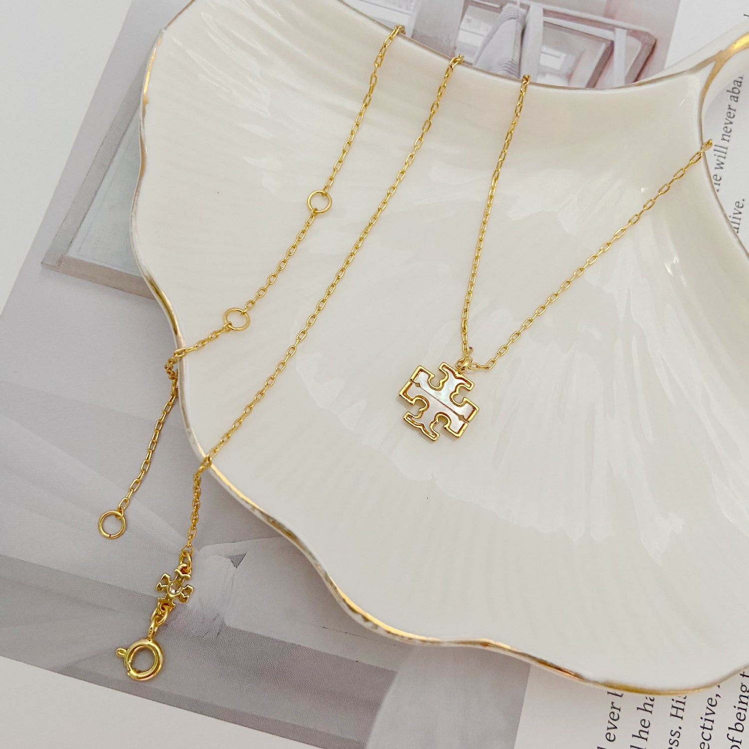 Gold-tone pendant necklace with interlocking logo charm on linked chain
