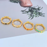 Gold-tone geometric circle ring set showing different enamel color accents (red/green)