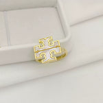 Gold logo ring set in a white jewelry box, featuring geometric cutouts