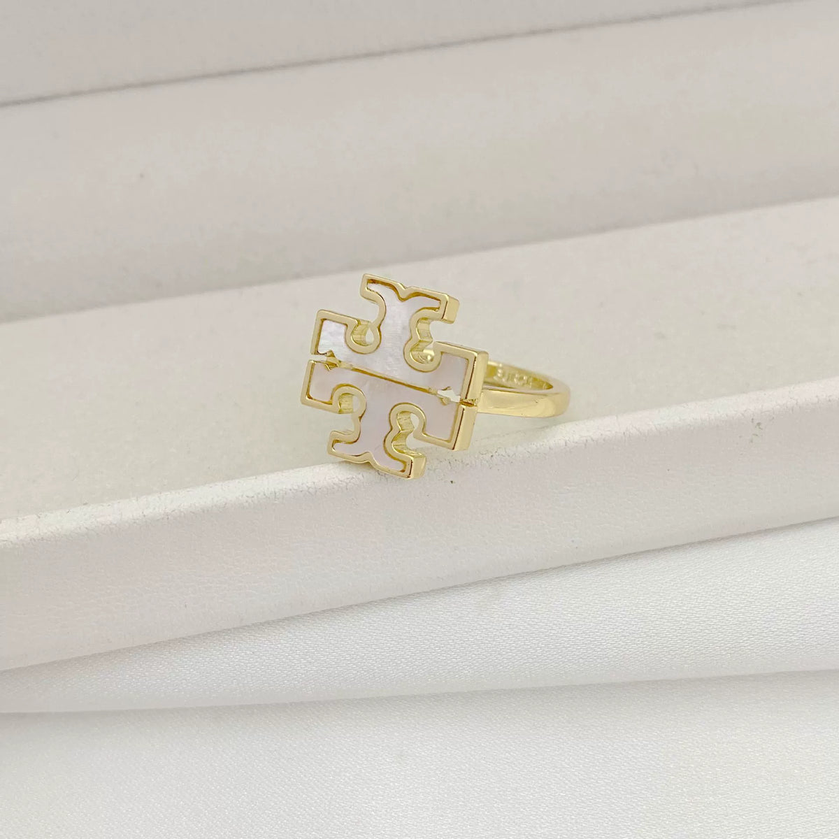 Gold logo ring with interlocking geometric cutouts and openwork front