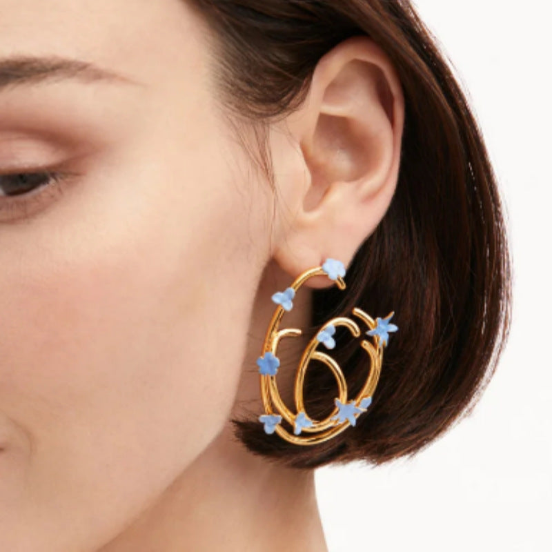 Gold hoop earrings with blue enamel clover and star charms
