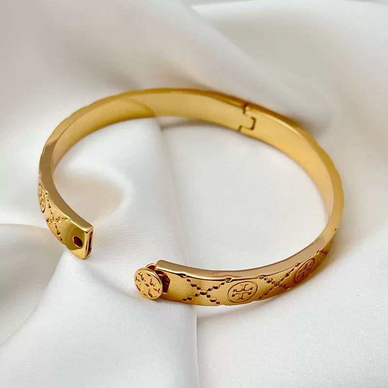 Gold logo-pattern hinged bracelet with hinge clasp and engraved oval medallions