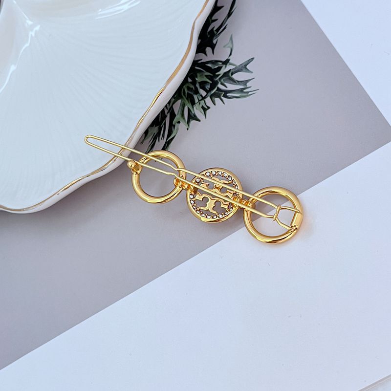Gold-tone round diamond hair clip with bar pins and pavé center disc