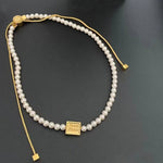 Pearl drawstring necklace with gold square tag and small gold caps at ends
