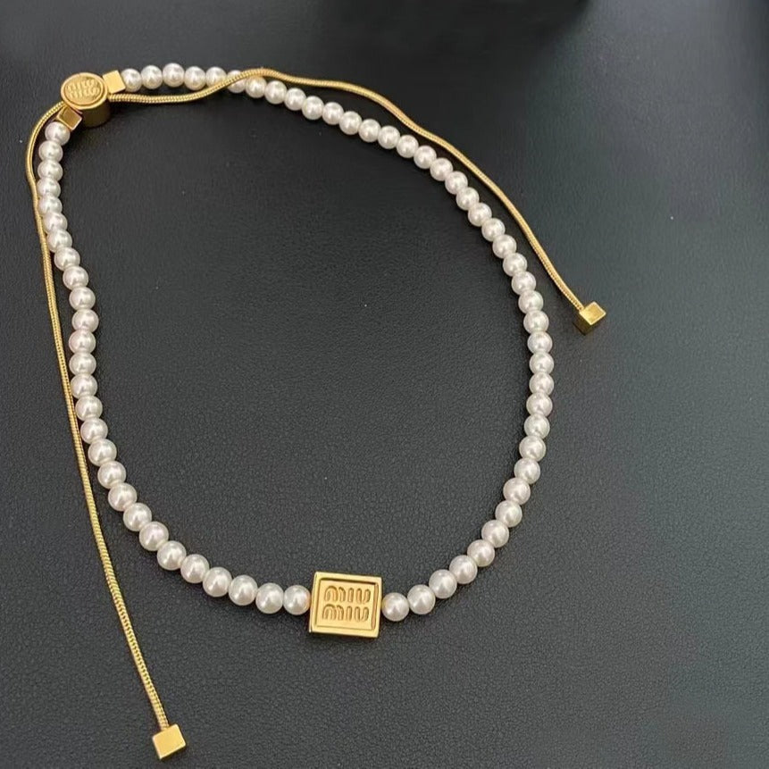 Pearl drawstring necklace with gold square tag and small gold caps at ends