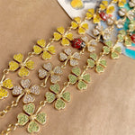 Gold clover necklace with green and clear textured petals and a red ladybug charm