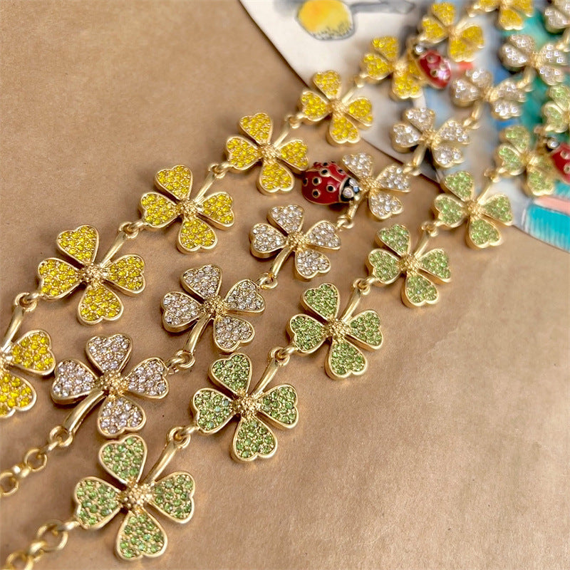 Gold clover necklace with green and clear textured petals and a red ladybug charm