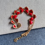Heart-shaped necklace with red enamel hearts, gold chain, and charm tag