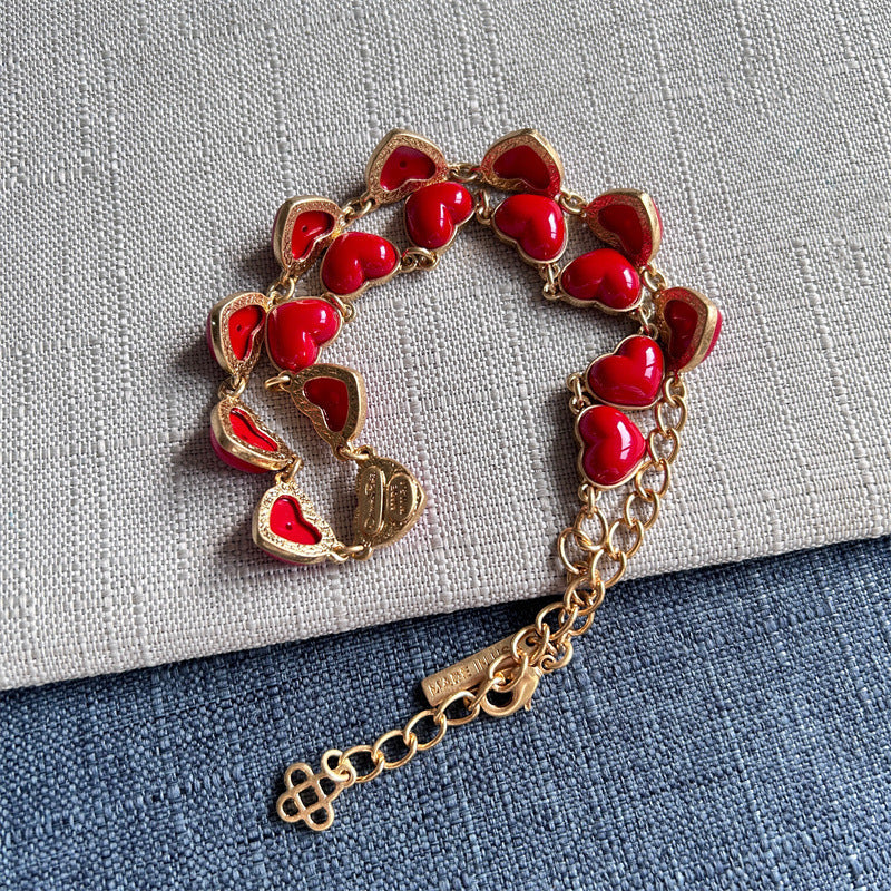 Heart-shaped necklace with red enamel hearts, gold chain, and charm tag