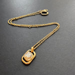 Gold-tone hammered square pendant necklace with faceted clear gemstone on chain